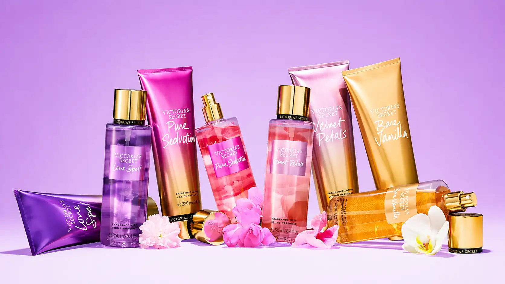 Une collection de produits de parfum Victoria’s Secret dans des emballages vibrants violet, rose et or, avec des bouchons métalliques élégants.