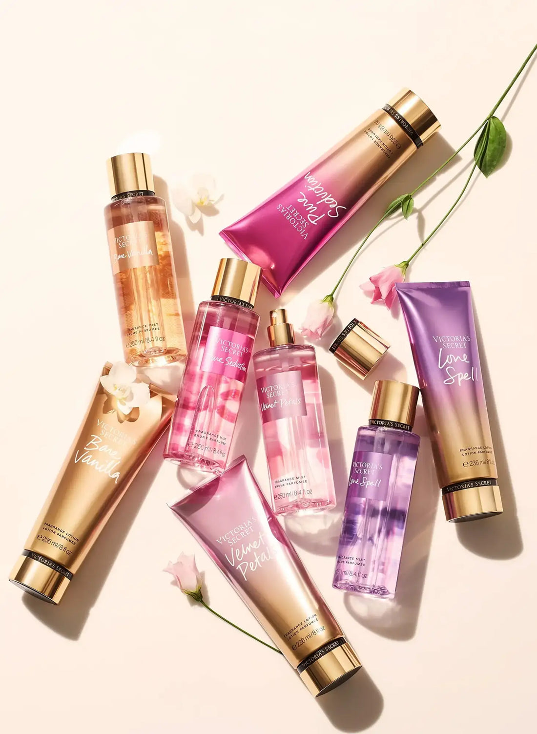 Une collection de produits de soins corporels Victoria's Secret dans un emballage dégradé rose, violet et or avec des capsules métalliques.