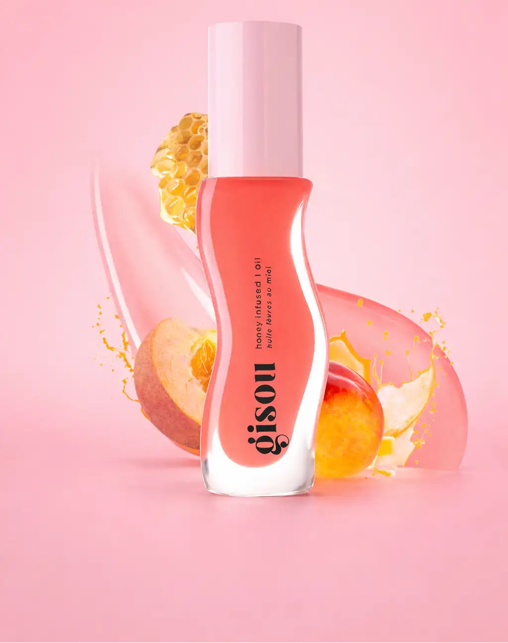 Une élégante bouteille en verre transparent avec un bouchon rose tendre contient un gloss pour les lèvres couleur pêche, infusé au miel, de la marque gisou.