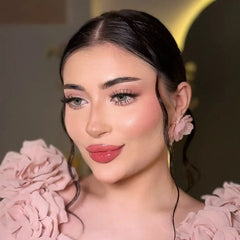 Une femme portant un haut à volants rose tendre avec des boucles d’oreilles florales assorties.