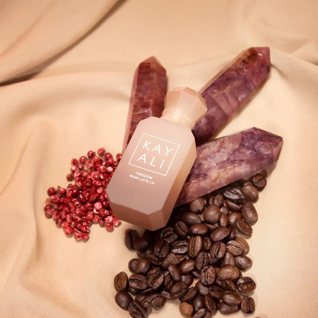 Un flacon de parfum mat couleur pêche, de forme géométrique, avec un capuchon assorti et une étiquette blanche minimaliste portant la mention « kay ali freedom musc latte 141 ».