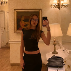 Sac à main en cuir noir avec une bandoulière à chaîne posé sur une surface en marbre