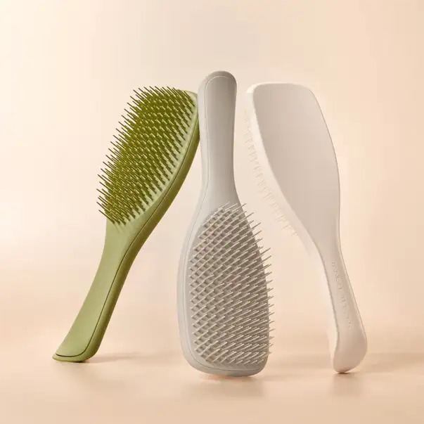 Trois élégantes brosses à cheveux modernes en vert sauge mat et blanc, avec des poignées ergonomiques et des poils denses.